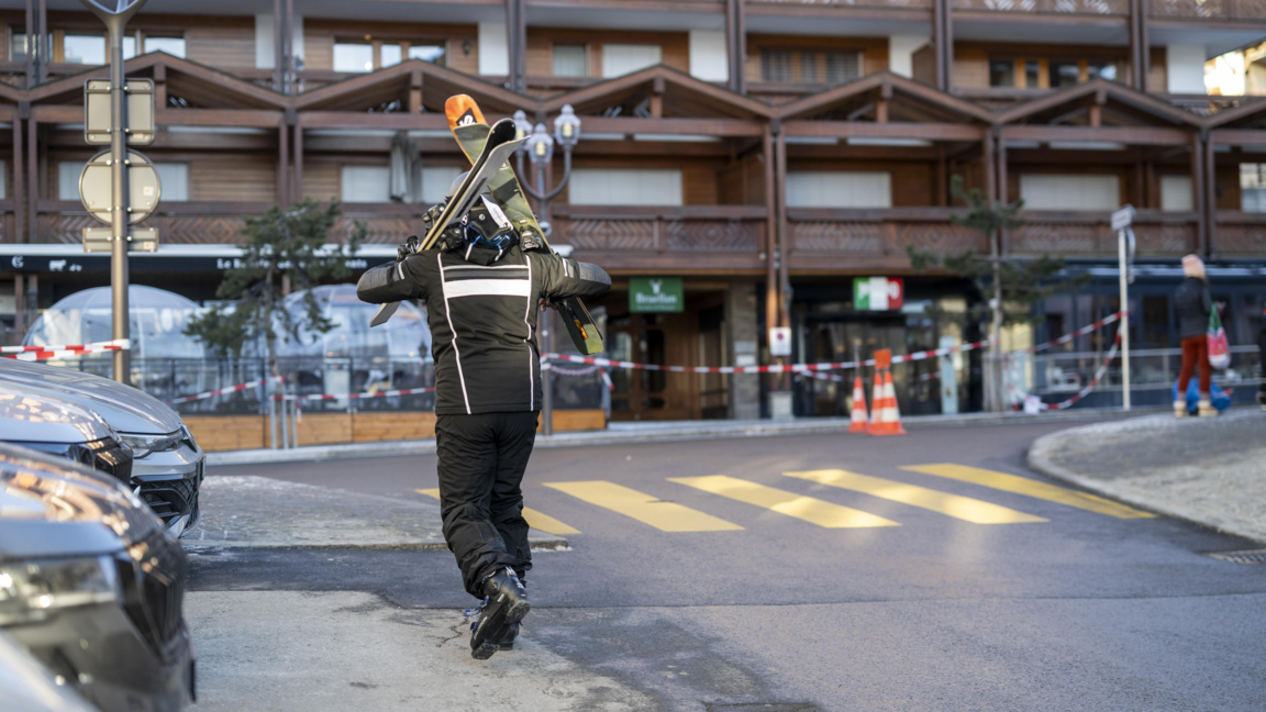 Скиор върви по улица близо до мястото, където избухна пожар в бар в Кран Монтана