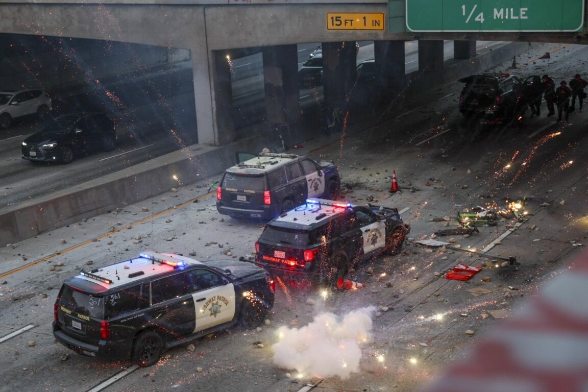 Полицейски служители се прикриват, докато активисти обсипват автомобили с камъни и фойерверки по време на протести, предизвикани от имиграционни акции в Лос Анджелис, Калифорния, САЩ, 8 юни 2025 г.