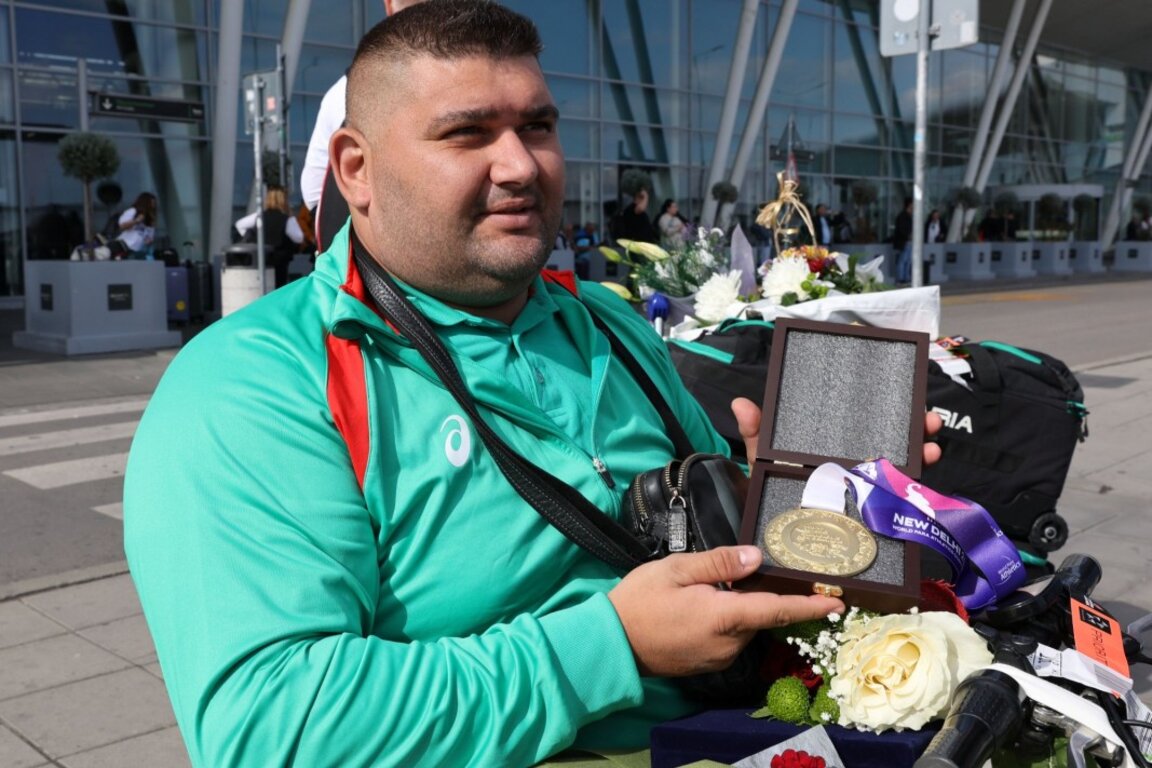 Ружди показва златния медал на летището.