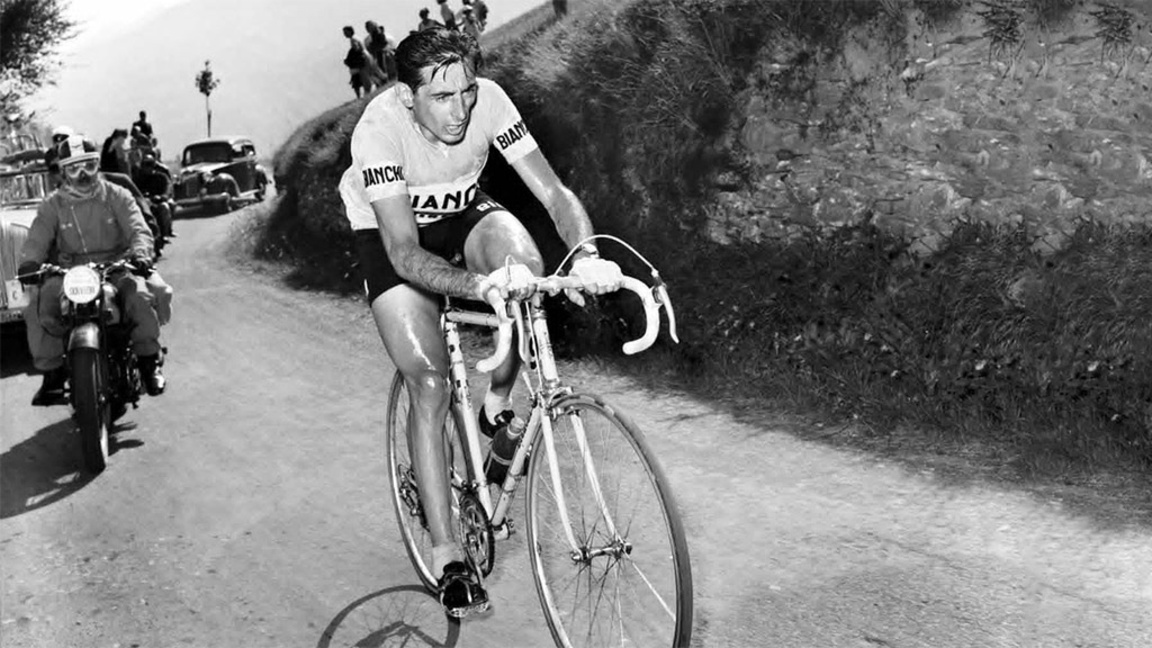 На тази емблематична снимка е Фаусто Копи (Fausto Coppi). Италианският колоездач е сред най-великите в историята. Наричан е "Il Campionissimo" (Шампионът на шампионите) и е сред малкото колоездачи, печелили трите големи обиколки (Франция, Италия и Испания)