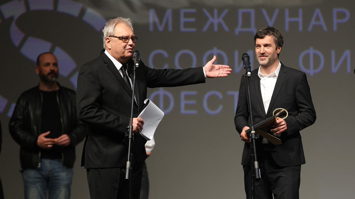 El fundador y director del festival internacional de cine "Sofía Film Fest", Stefan Kitanov —Kita (a la izquierda) entrega el premio al director de la película "El director", Ondřej Provazník.