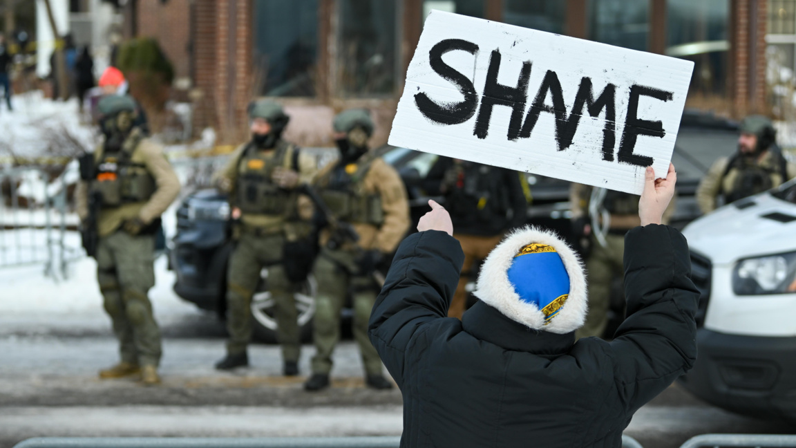 Жена издига плакат с надпис "Срам" на мястото на стрелбата по Рене Гуд в Минеаполис