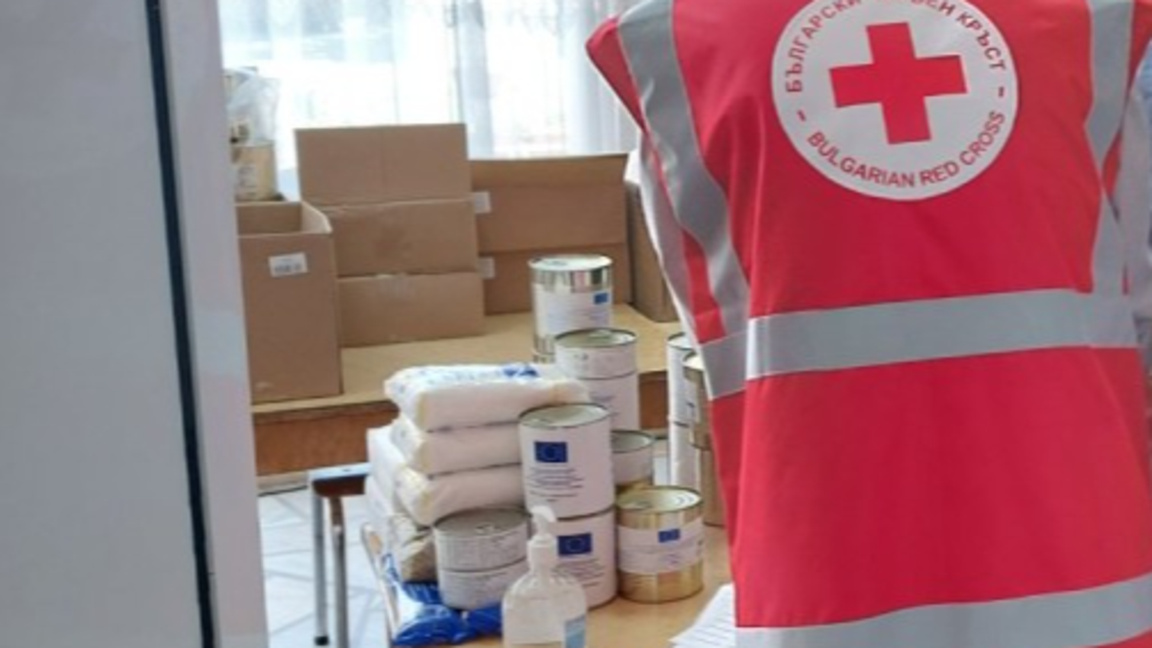 Служители и доброволци на БЧК раздават пакети с храна