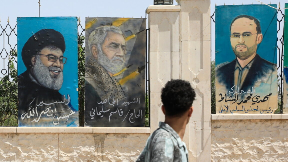 Мъж гледа картини, изобразяващи (отляво надясно) покойния лидер на "Хизбула" Хасан Насрала и убития ирански генерал Касем Солеймани, поставени до портрет на председателя на Върховния политически съвет на йеменските хути Махди ал-Машат на ограда в Сана, Йемен, 28 септември 2024 г.