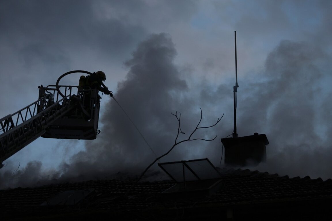 Пожарникар гаси пожар, избухнал в къща.